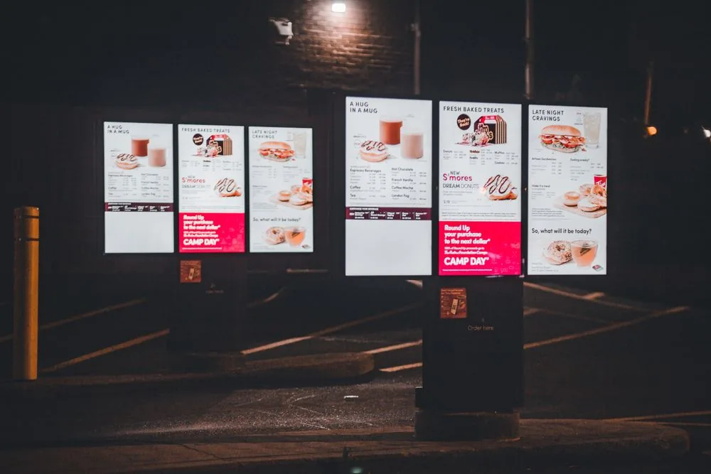 Weatherproof digital menu totems lit at night outdoors
