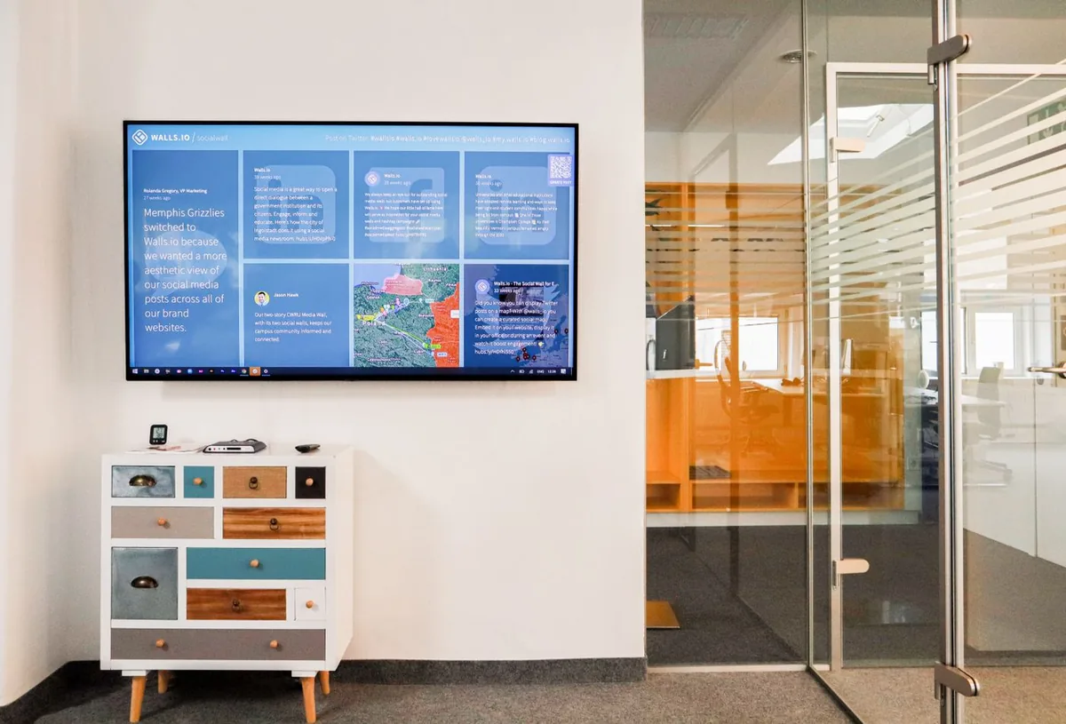 Wall-mounted commercial display in a modern office showing a live feed