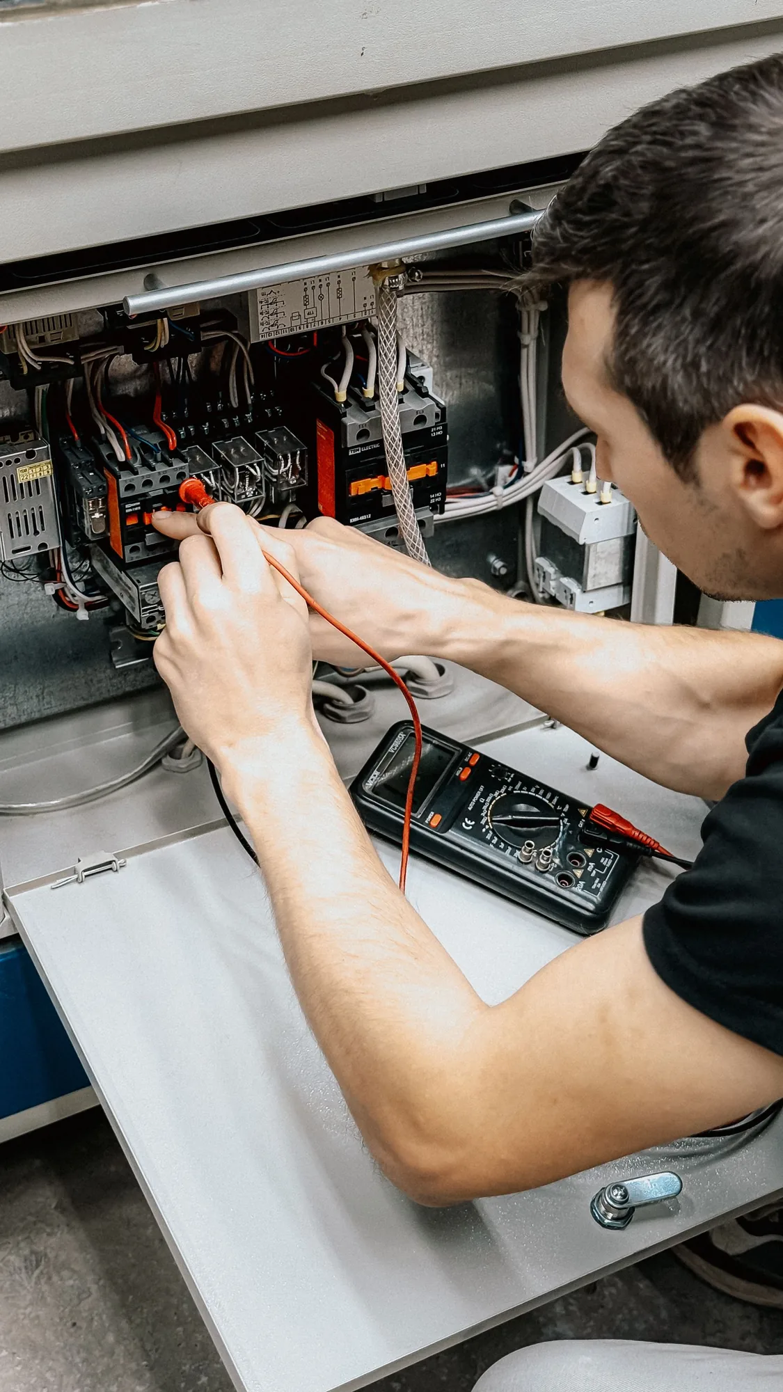 Licensed electrician testing an electrical panel in a Singapore home