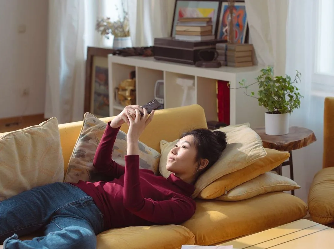 A homeowner on the sofa answering the gate on her phone through the Hik-Connect app