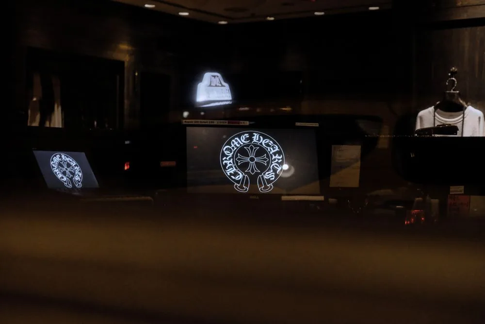 Digital screen displaying a brand logo behind a retail glass frontage at night